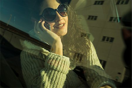 Close-up of teenage girl sitting in car, wearing sunglasses and talking on cell phone, Germany Photographie de stock - Premium Libres de Droits, Code: 600-07311091