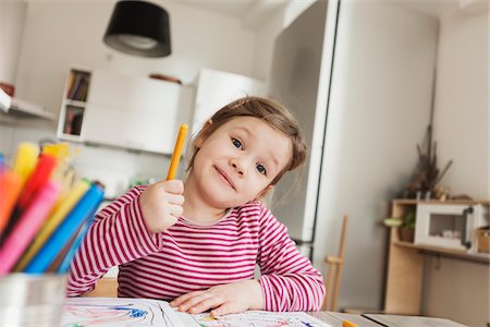 Girl sitting at Table Colouring Pictures and Smiling at Camera Stock Photo - Premium Royalty-Free, Code: 600-07311312