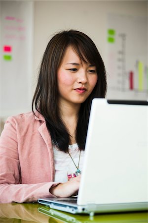 simsearch:600-07202762,k - Young woman working on laptop computer in office, Germany Stock Photo - Premium Royalty-Free, Code: 600-07311396