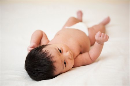 simsearch:700-07311591,k - Newborn Asian baby in diaper lying on back, scratching head from baby acne, studio shot on white background Stock Photo - Premium Royalty-Free, Code: 600-07453947