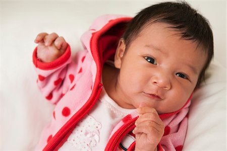 simsearch:700-07311591,k - Close-up portrait of two week old Asian baby girl in pink polka dot jacket, smiling and looking at camera, studio shot Stock Photo - Premium Royalty-Free, Code: 600-07453964