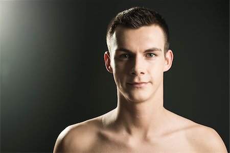 Close-up portrait of young man looking at camera, studio shot on black background Stock Photo - Premium Royalty-Free, Code: 600-07567372