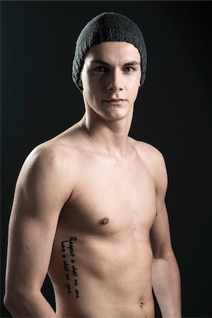 side (anatomy) - Close-up portrait of young man wearing toque, studio shot on black background Stock Photo - Premium Royalty-Free, Code: 600-07567381