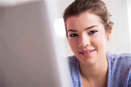 school work - Close-up of young woman working in office on desktop PC, looking at camera and smiling, Germany Photographie de stock - Premium Libres de Droits, Code: 600-07584758