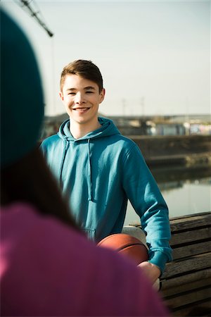 simsearch:600-06961037,k - Teeange boy holding basketball outdoors, smiling and looking at teenage girl, industrail area, Mannheim, Germany Stock Photo - Premium Royalty-Free, Code: 600-07584779