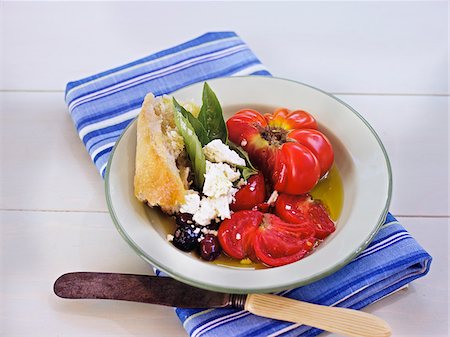 Fresh Salad with Heirloom Tomatoes, Kalamata Olives, Baguette, Basil and Cheese on White Table, Outdoors, Canada Stock Photo - Premium Royalty-Free, Code: 600-07945334
