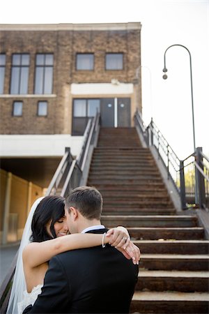 simsearch:700-07199878,k - Portrait of Bride and Groom Hugging at Bottom of Staircase Outdoors, Hamilton, Ontario, Canada Stock Photo - Premium Royalty-Free, Code: 600-07991599