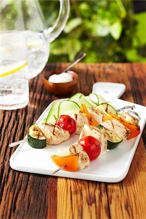 platter - BBQ Chicken and vegetable skewers on a white serving platter with lemon sparkling water on a wood picnic table, studio shot Stock Photo - Premium Royalty-Free, Code: 600-08002091