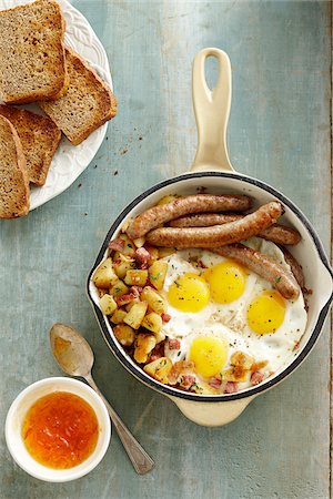 simsearch:600-06752237,k - Overhead View of Skillet with Sunny Side up Eggs, Sausage, and Hashbrowns served with Whole Wheat Toast and Apricot Jam on Wooden Background Stock Photo - Premium Royalty-Free, Code: 600-08002385