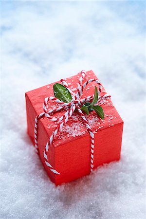 Red Christmas Gift Box with Boxwood Leaves and Candy Cane Ribbon on Surface of Snow Stock Photo - Premium Royalty-Free, Code: 600-08167380