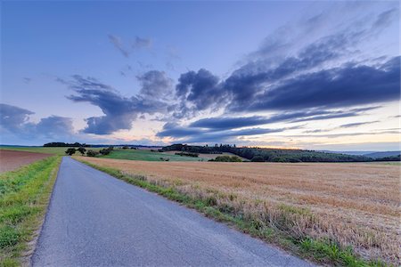 simsearch:600-08973340,k - Countryside with harvested cereal field and paved laneway at dusk in summer at Roellbach in Spessart hills in Bavaria, Germany Stock Photo - Premium Royalty-Free, Code: 600-08973335