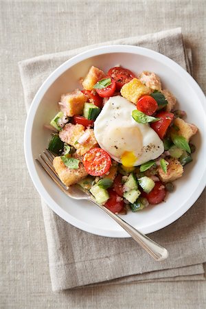 Panzanella bread salad with a poached egg in a white bowl on a beige linen background Stock Photo - Premium Royalty-Free, Code: 600-09119334