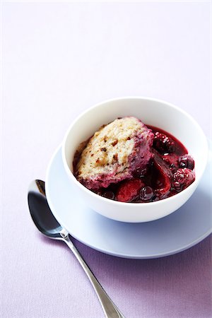 Bowl of berry fruit cobbler with a biscuit topping and a spoon on a purple background Stock Photo - Premium Royalty-Free, Code: 600-09119375