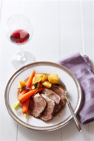 simsearch:600-02912202,k - Dinner plate of lamb with carrots, potatoes and a glass of red wine with a purple napkin Stock Photo - Premium Royalty-Free, Code: 600-09119381