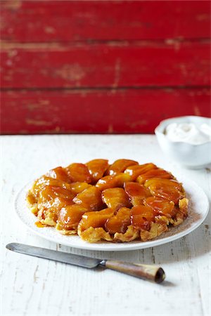 Apple tart tatin on plate with whipping cream and a serving knife Stock Photo - Premium Royalty-Free, Code: 600-09119403