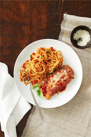 simsearch:600-06382994,k - Plate of chicken parmesan with spaghetti and tomato sauce and a side dish of cheese with a fork and napkin on a wooden background Stock Photo - Premium Royalty-Free, Code: 600-09155499