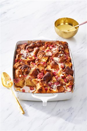 simsearch:600-06671821,k - Rhubarb bread pudding in a casserole dish with gold serving spoon and a bowl of custard Photographie de stock - Premium Libres de Droits, Code: 600-09155584
