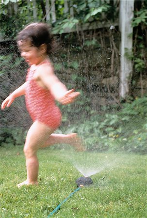 Blurred View of Girl in Swimwear Playing in Sprinkler Stock Photo - Premium Royalty-Free, Code: 600-00034267