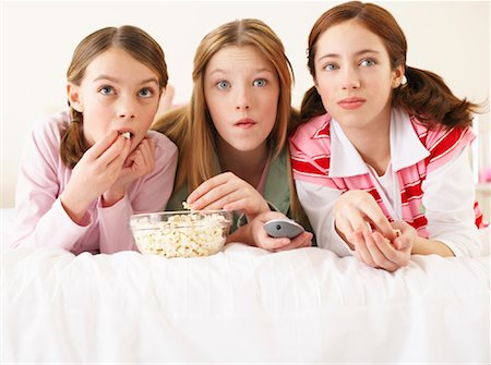 Girls Lying on Bed, Eating Popcorn Foto de stock - Sin royalties Premium, Código: 600-00866169