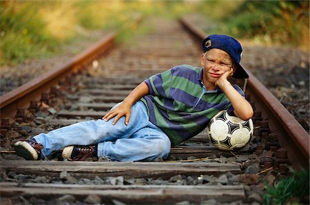 Boy With Soccer Ball Lying Down In Train Tracks Photographie de stock - Premium Libres de Droits, Code: 600-00948336