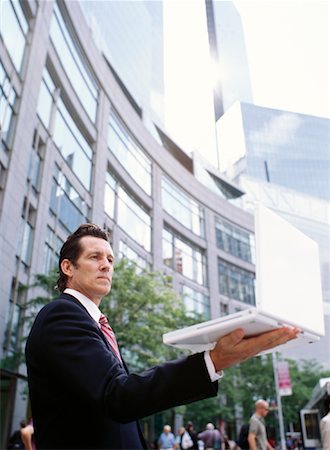 simsearch:700-00281308,k - Businessman Holding Laptop Computer in City Stock Photo - Premium Royalty-Free, Code: 600-00948870