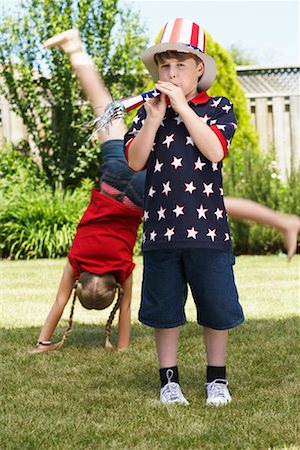 simsearch:700-00092986,k - Boy Wearing Stars and Stripes Top and Hat, Girl doing Cartwheel in Background Stock Photo - Premium Royalty-Free, Code: 600-01042009