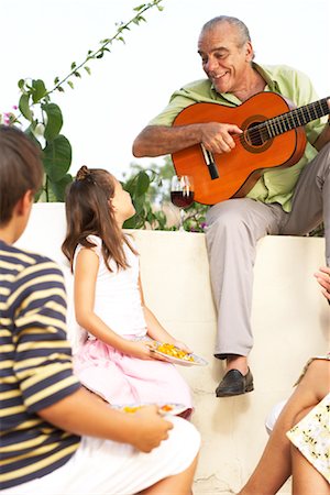 Jouer de la guitare à l'extérieur avec des enfants à l'écoute de l'homme Photographie de stock - Premium Libres de Droits, Code: 600-01043408