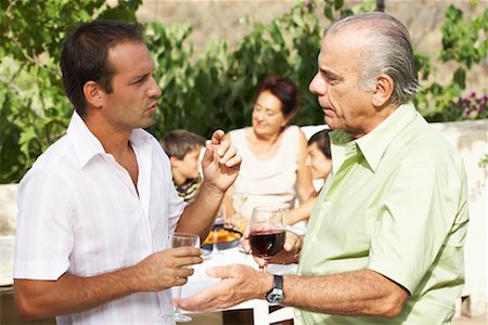 Father and Son Talking, with other Family Members in Background Stock Photo - Premium Royalty-Free, Code: 600-01043402