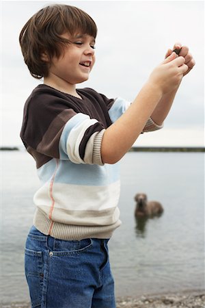 Boy Looking at Stone on Beach Stock Photo - Premium Royalty-Free, Code: 600-01123682