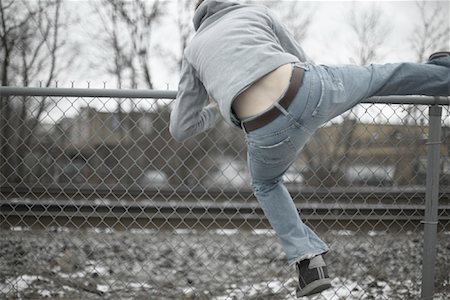 running away scared - Man Climbing over Fence Stock Photo - Premium Royalty-Free, Code: 600-01184408