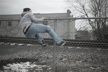 running away scared - Man Climbing over Fence Stock Photo - Premium Royalty-Free, Code: 600-01184409