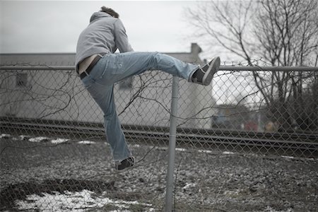 running away scared - Man Climbing over Fence Stock Photo - Premium Royalty-Free, Code: 600-01184410