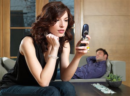 simsearch:700-01199784,k - Woman Using Cell Phone and Man Lying on Sofa in Background Stock Photo - Premium Royalty-Free, Code: 600-01276508