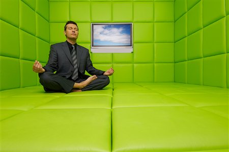 Businessman Meditating in Green Padded Room with Television Stock Photo - Premium Royalty-Free, Code: 600-01407171