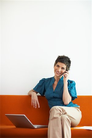Woman with Cellular Phone and Laptop Computer on Sofa Stock Photo - Premium Royalty-Free, Code: 600-01464403