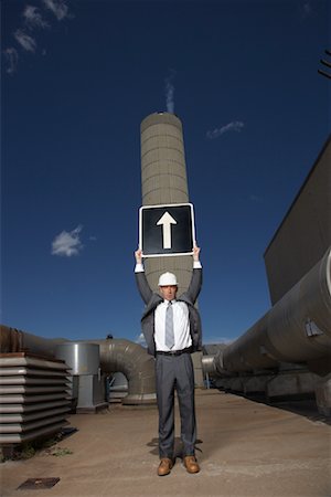 Businessman Holding Arrow Sign Outside Factory Stock Photo - Premium Royalty-Free, Code: 600-01582103