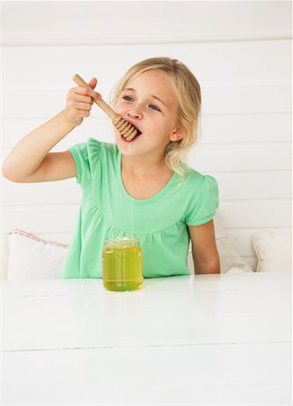 Little Girl Eating Honey Stock Photo - Premium Royalty-Free, Code: 600-01616965