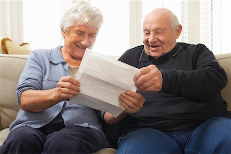 Senior Couple Sitting on Sofa Looking at Document Together Stock Photo - Premium Royalty-Free, Code: 600-01716143
