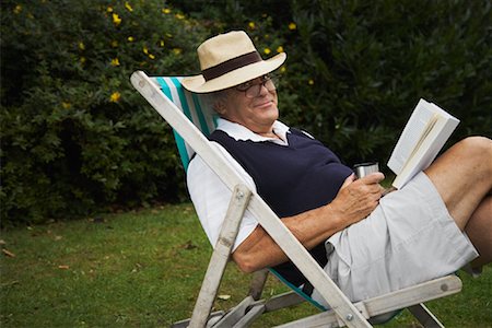 Man Sitting in Lawn Chair, Reading Book Stock Photo - Premium Royalty-Free, Code: 600-01717985