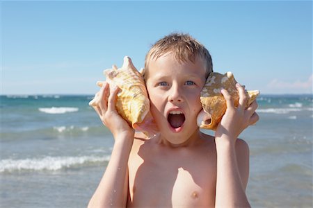 Boy Holding Seashells to His Ears, Elmvale, Ontario, Canada Stock Photo - Premium Royalty-Free, Code: 600-02265288