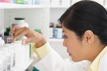 Pharmacist Looking at Pills on Shelf Stock Photo - Premium Royalty-Free, Code: 600-02265333