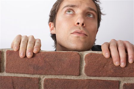 Man Looking Over Brick Wall Stock Photo - Premium Royalty-Free, Code: 600-02312393