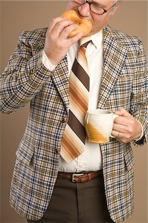 Retro Businessman Eating a Doughnut and Drinking a Cup of Coffee Stock Photo - Premium Royalty-Free, Code: 600-02757029