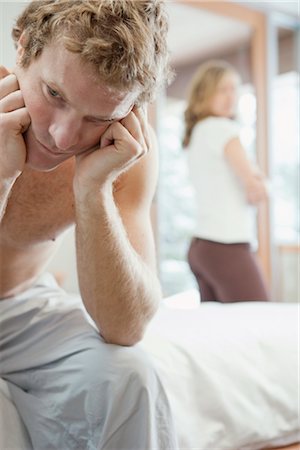 sad lovers break up - Homme assis sur le bord du lit et la femme se tenant près de fenêtre en arrière-plan Photographie de stock - Premium Libres de Droits, Code: 600-02757310