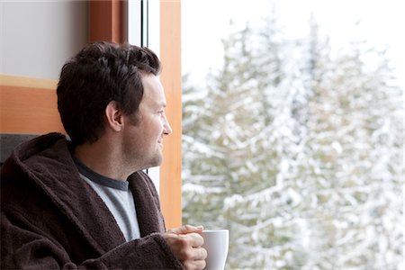 Man in Bathrobe Holding a Cup of Coffee and Gazing Out the Window Stock Photo - Premium Royalty-Free, Code: 600-02757322