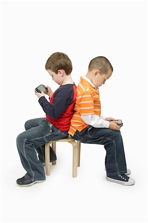 Boys with Handheld Video Games Sitting Back to Back Stock Photo - Premium Royalty-Free, Code: 600-03017563