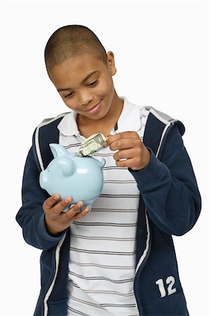 Boy Putting Money in Piggy Bank Stock Photo - Premium Royalty-Free, Code: 600-03017571