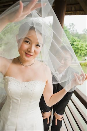simsearch:600-03333357,k - Bride and Groom Peeking Through Veil Stock Photo - Premium Royalty-Free, Code: 600-03333307