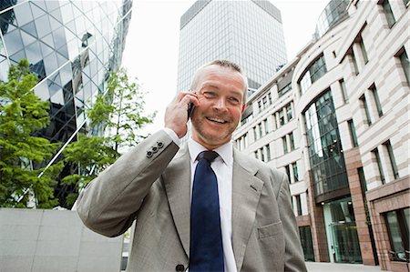 Businessman in city on cellphone Stock Photo - Premium Royalty-Free, Code: 614-05556712