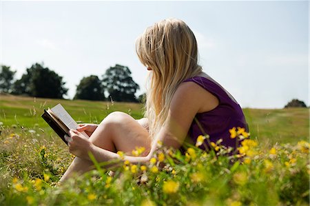 Young woman reading a book in a field Stock Photo - Premium Royalty-Free, Code: 614-05557081